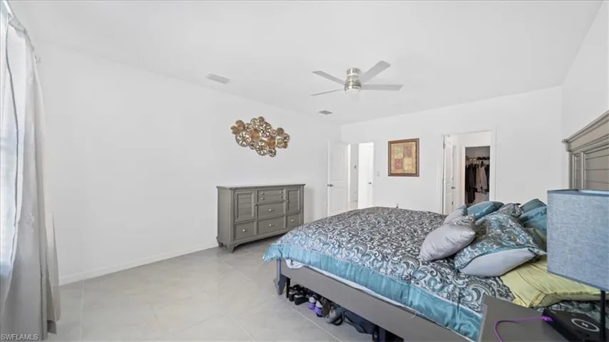Bedroom with ceiling fan, a spacious closet, and light tile patterned floors