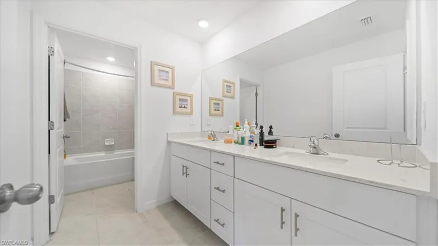 Full bathroom with double vanity, light tile patterned flooring, shower / tub combination, and recessed lighting