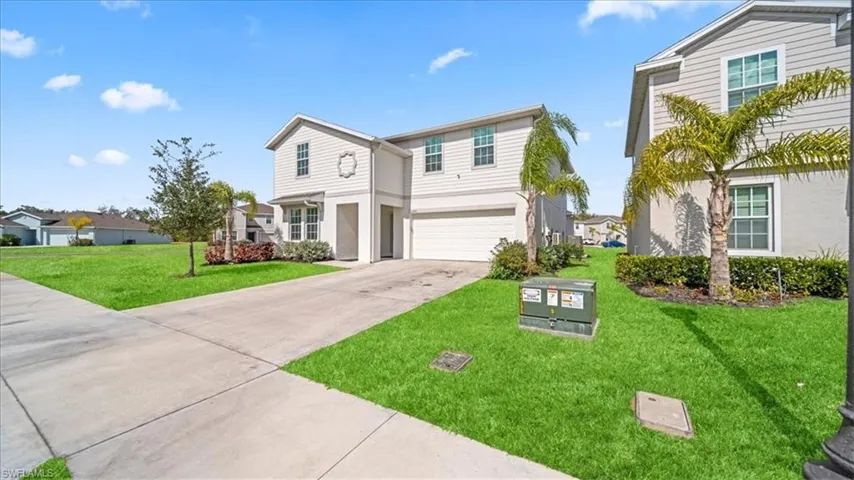 Traditional-style home with an attached garage, a front lawn, concrete driveway, stucco siding, and a residential view