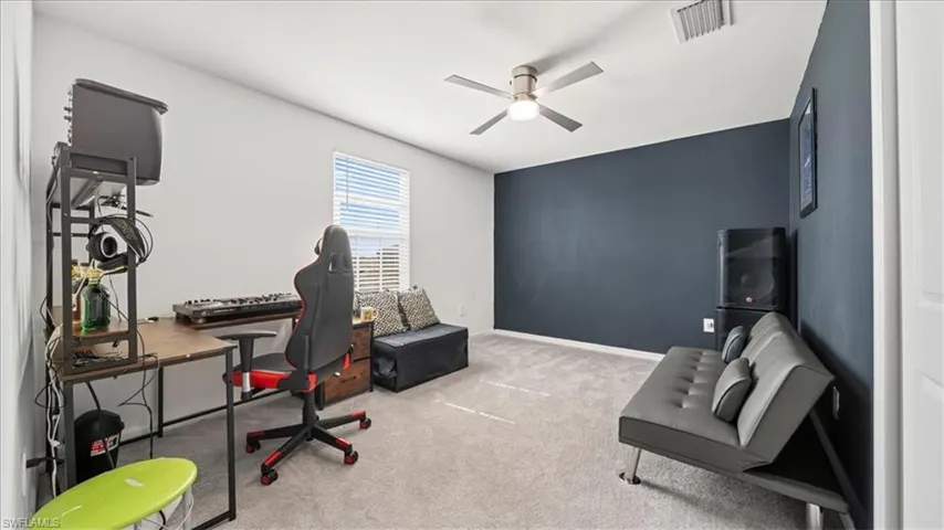 Office area featuring light colored carpet, ceiling fan, and an accent wall