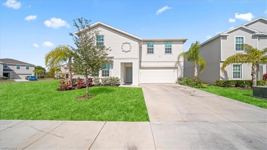 Traditional-style house with a front yard, a garage, concrete driveway, and stucco siding