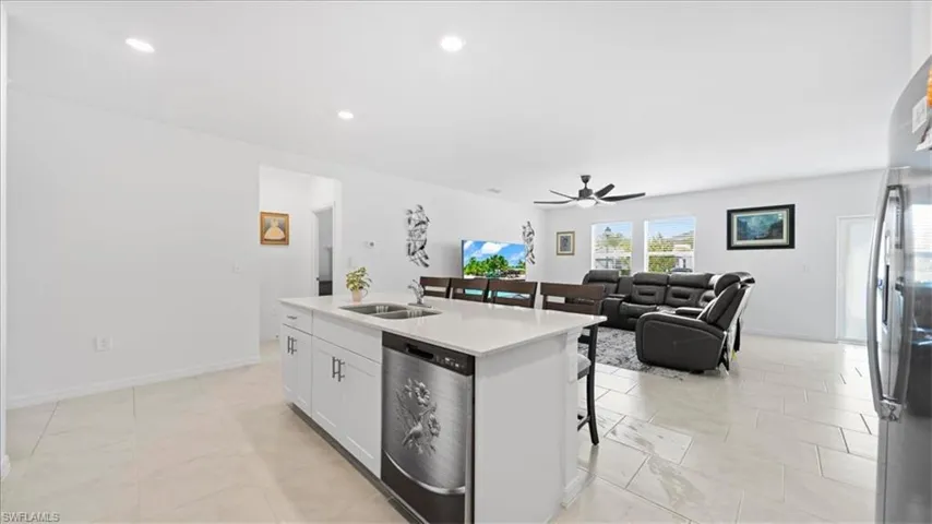 Kitchen with a kitchen bar, open floor plan, stainless steel appliances, white cabinetry, and a kitchen island with sink