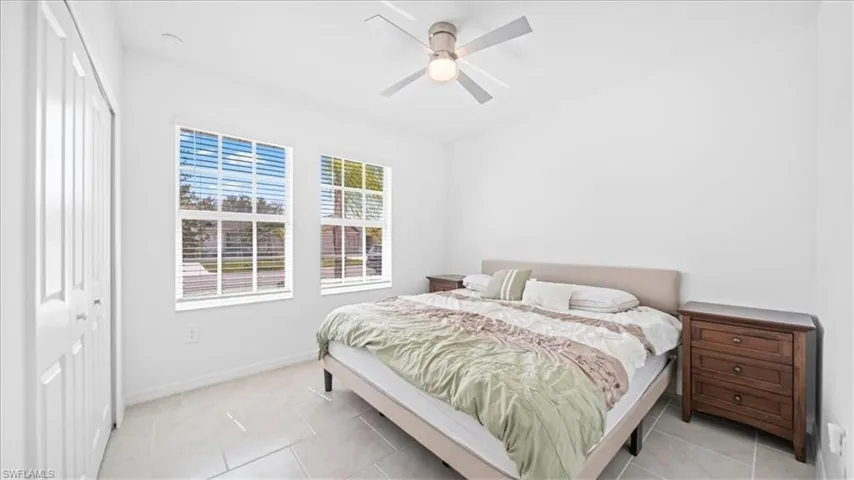 Bedroom featuring a ceiling fan, light tile patterned floors, and a closet