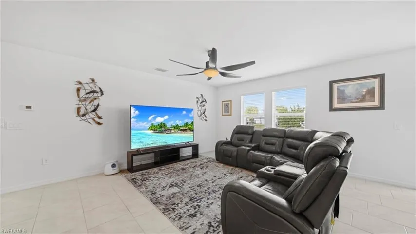 Living room with light tile patterned floors and a ceiling fan