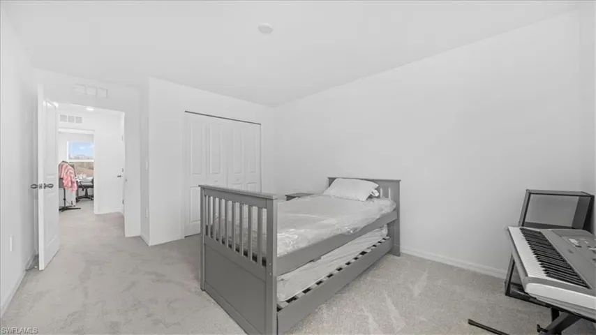 Bedroom featuring light carpet and a closet