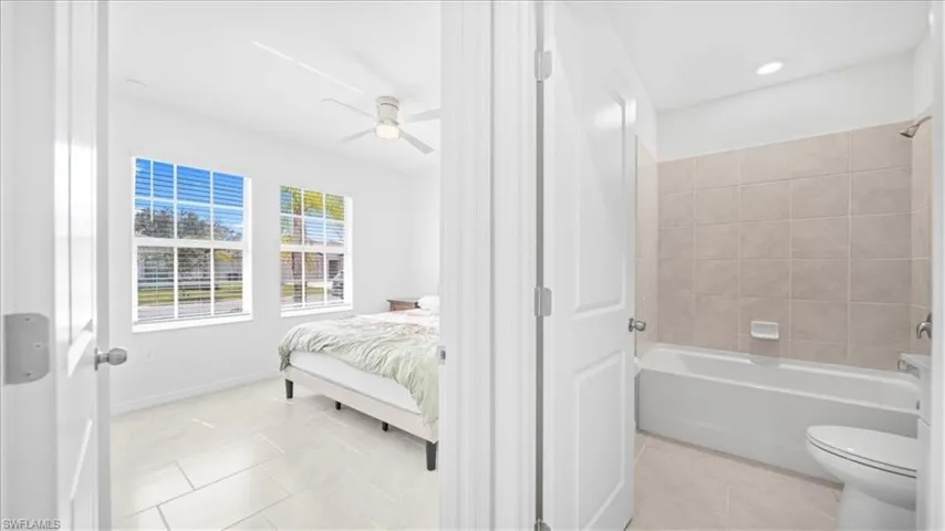 Ensuite bathroom with light tile patterned flooring, shower / bathtub combination, ceiling fan, and recessed lighting