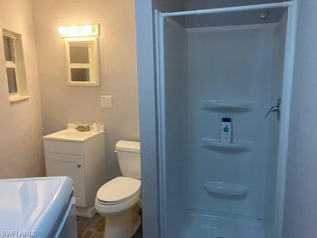 Bathroom featuring a shower stall, vanity, washer / clothes dryer, and dark tile patterned floors