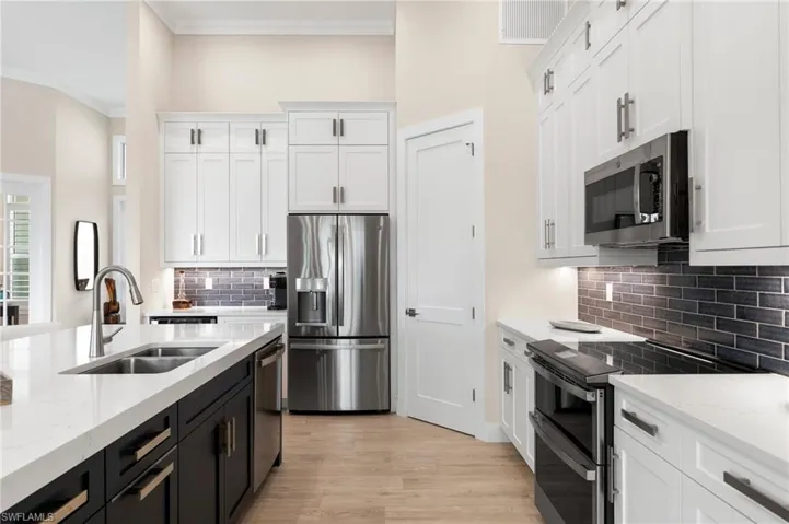 Kitchen with sink, white cabinets, appliances with stainless steel finishes, and tasteful backsplash