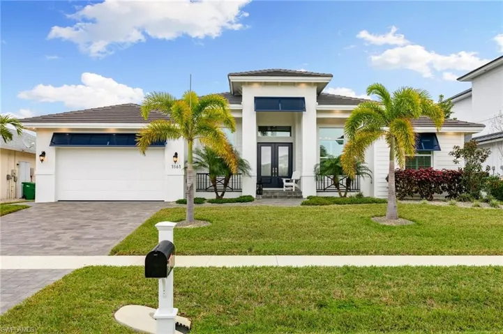 View of front facade with a garage, a front yard, and french doors