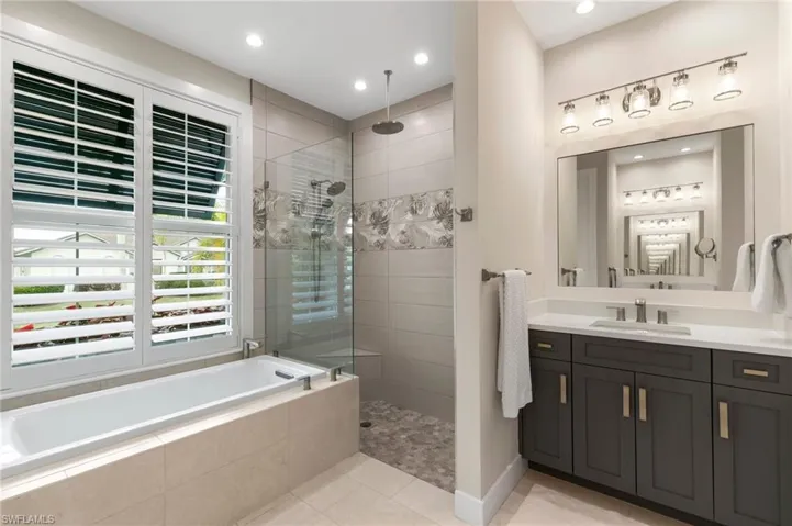 Bathroom with tile patterned flooring, vanity, and plus walk in shower