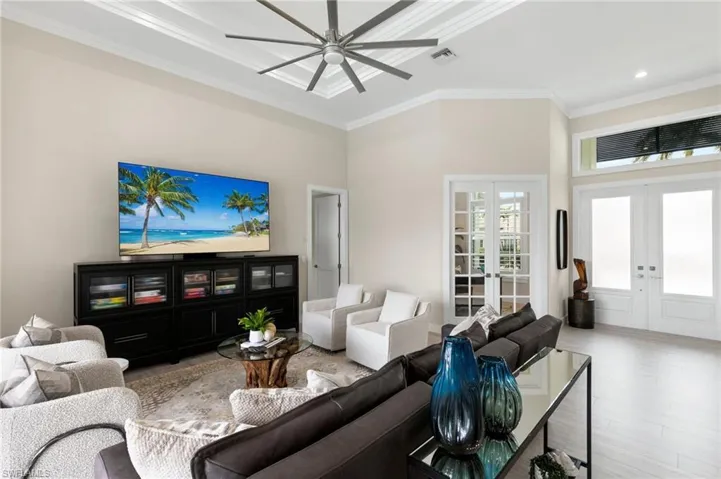 Living room featuring french doors, a high ceiling, crown molding, and light hardwood / wood-style floors