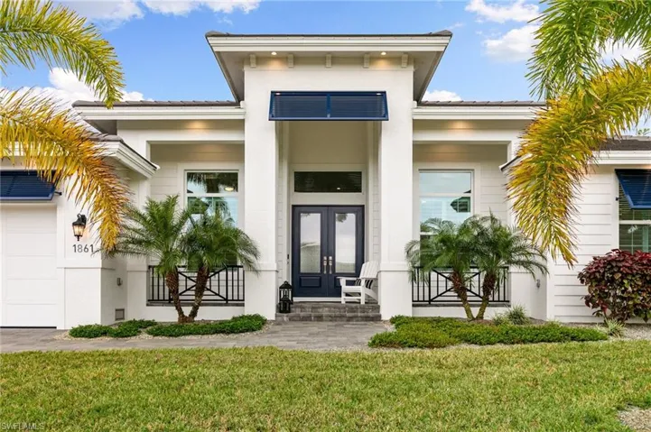 View of exterior entry with french doors and a lawn