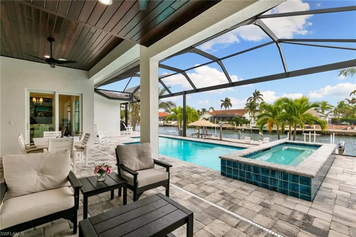 View of pool with an in ground hot tub, a lanai, a patio, a water view, and an outdoor hangout area