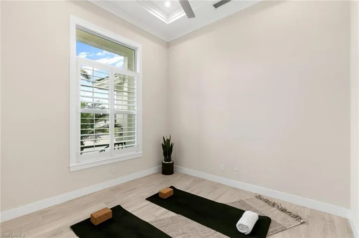 Exercise area featuring light wood-type flooring and ornamental molding