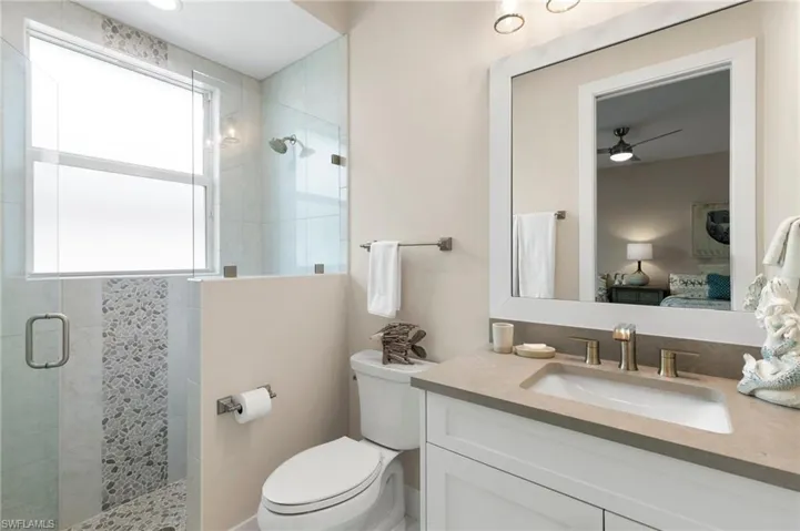 Bathroom featuring toilet, walk in shower, and vanity
