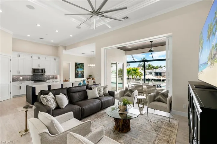 Living room with light hardwood / wood-style flooring, ornamental molding, and an inviting chandelier
