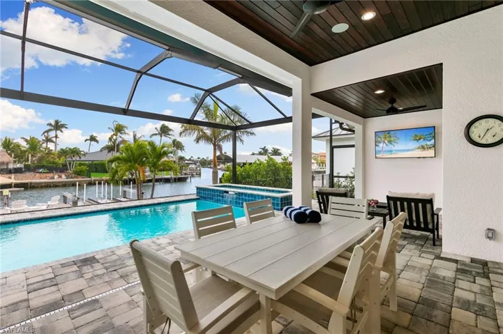 View of swimming pool with screen enclosure, ceiling fan, a patio area, and an in ground hot tub