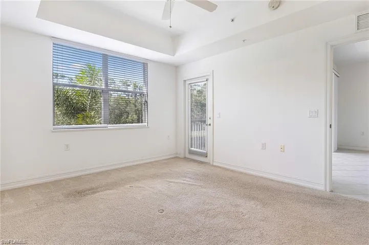 Master Bedroom with Light Carpet, Tray Ceiling, Ceiling Fan & Door to the Lanai!