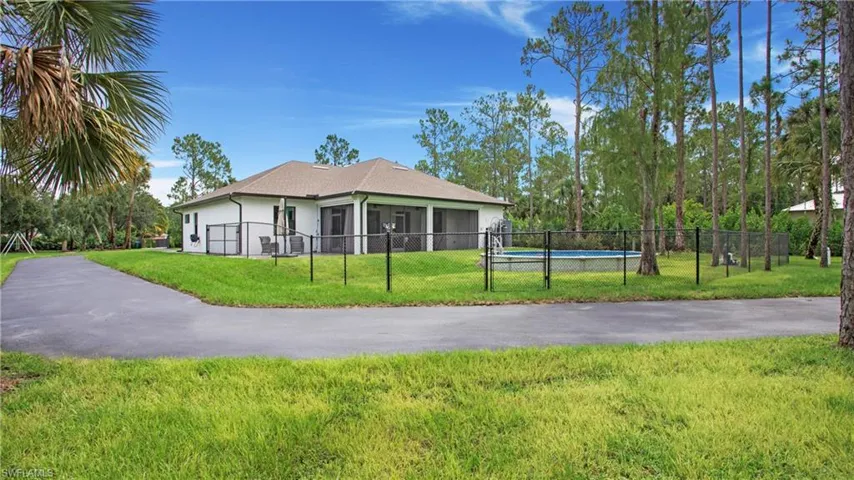 View of side of property featuring stucco siding and an attached garage, fence and above ground pool