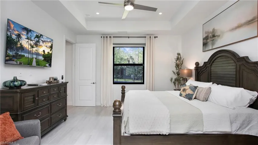 Bedroom featuring a raised ceiling, light wood finished floors, recessed lighting, and ceiling fan