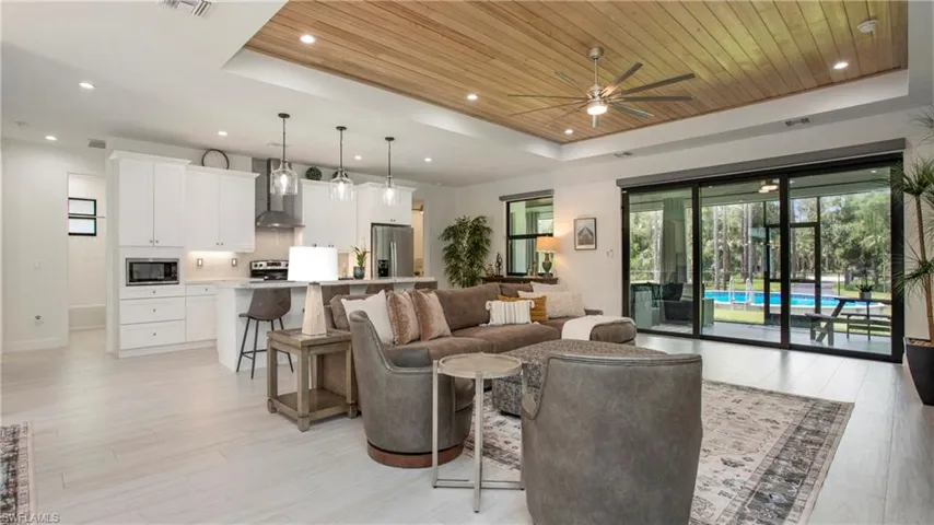 Living area with a raised ceiling, wood ceiling, ceiling fan, light wood-style floors, and recessed lighting