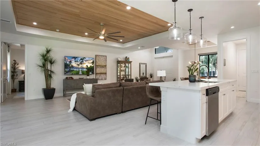 Kitchen featuring a raised ceiling, dishwasher, white cabinets, open floor plan, and recessed lighting