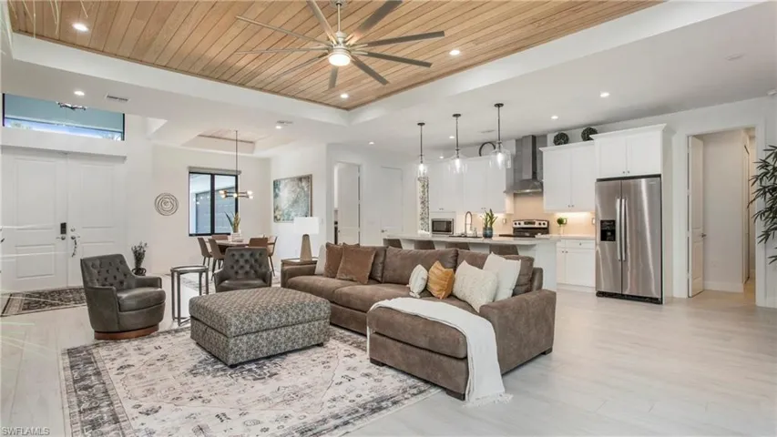 Living room featuring a tray ceiling, wooden ceiling, ceiling fan, light wood-type flooring, and recessed lighting