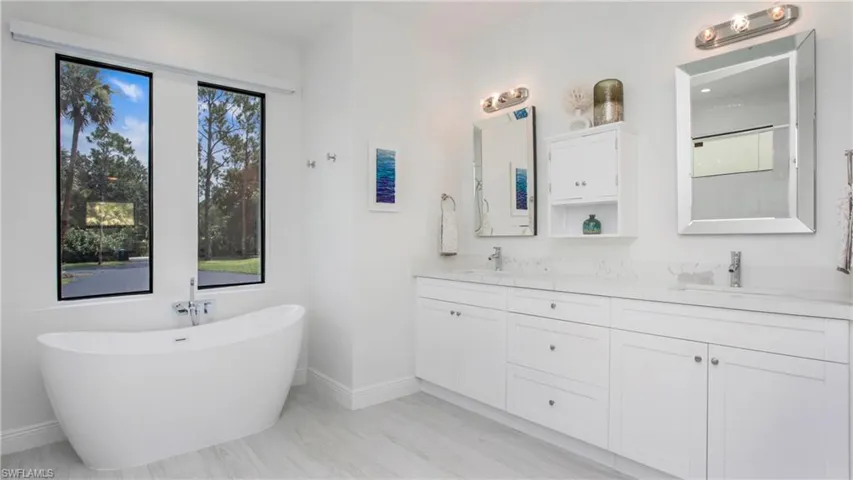 Bathroom with double vanity, a freestanding bath, and healthy amount of natural light