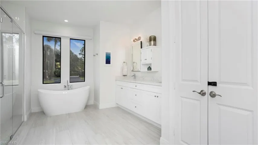 Full bathroom with vanity, a shower stall, a freestanding bath, and recessed lighting
