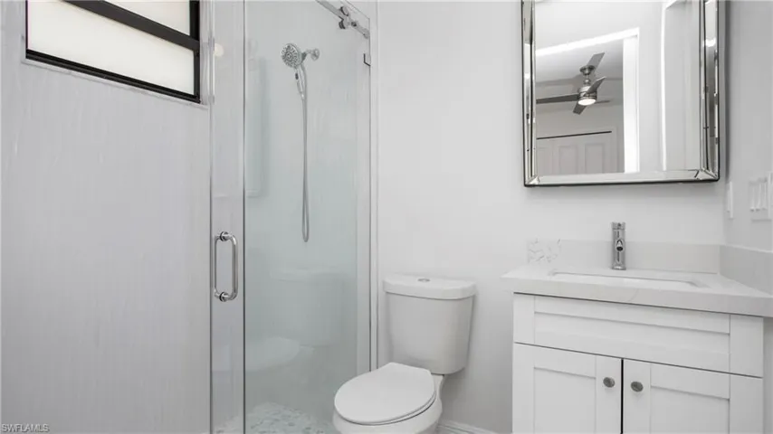 Bathroom with vanity, a stall shower, and a ceiling fan