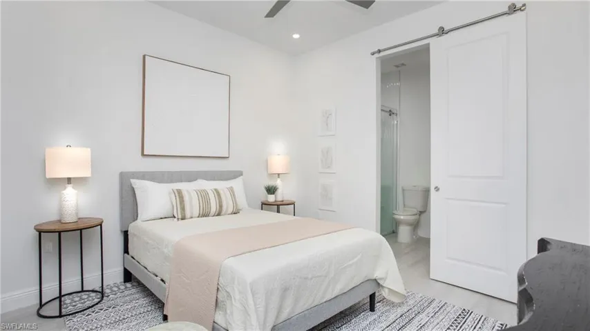 Bedroom featuring connected bathroom, recessed lighting, light wood finished floors, ceiling fan, and a barn door
