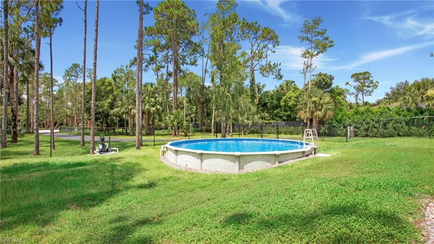 View of swimming pool featuring view of wooded area
