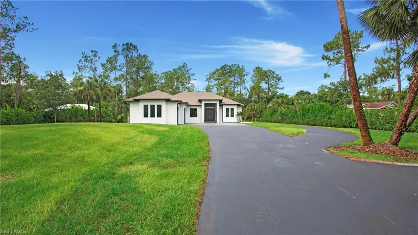 View of front of property with a front yard, driveway, and stucco siding