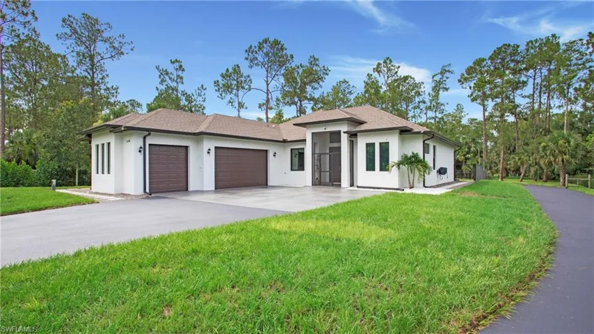 Prairie-style home with a garage, driveway, stucco siding, and a front yard