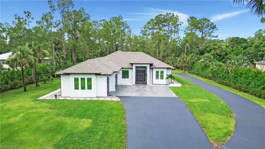View of front facade with driveway, stucco siding, and a front yard