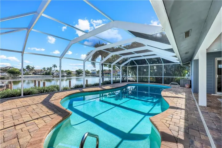 Swimming pool featuring a patio, a sunroom, a lanai, and a water view