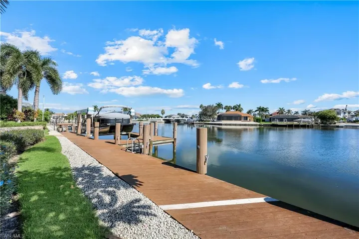 Dock featuring a water view, boat lift, and a residential view