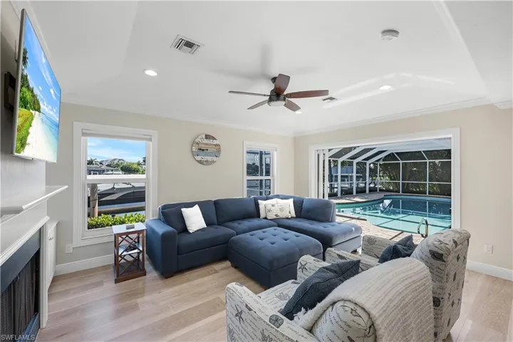Living area featuring ornamental molding, light wood-style flooring, a fireplace, ceiling fan, and recessed lighting