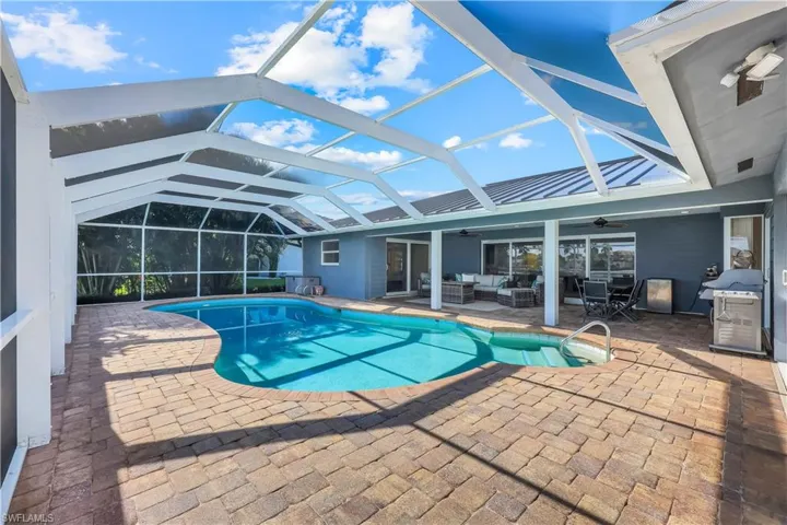 Swimming pool featuring an outdoor living space, glass enclosure, a patio, a sunroom, and a ceiling fan
