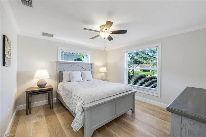 Bedroom featuring ornamental molding, light wood finished floors, multiple windows, and a ceiling fan