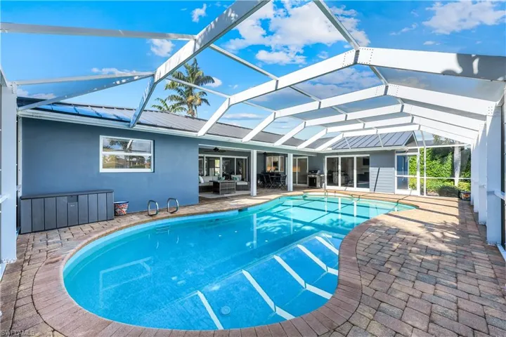 Swimming pool with glass enclosure, a patio area, outdoor lounge area, a sunroom, and a ceiling fan