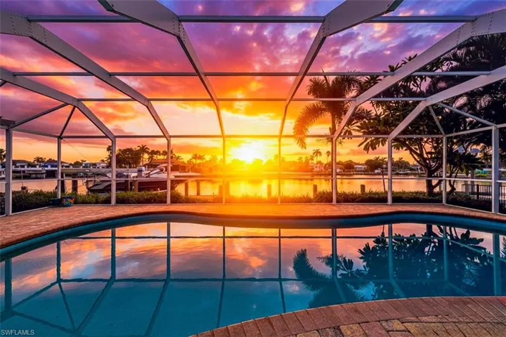 Pool at sunrise with a lanai, an outdoor pool, and a water view