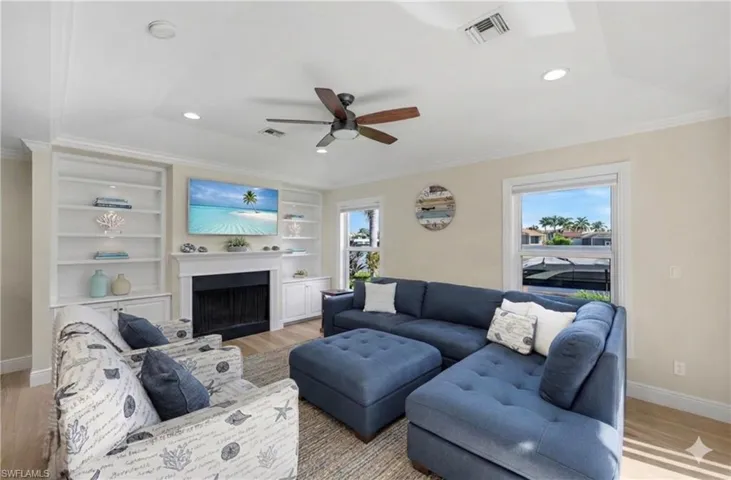 Living room with light wood-type flooring, crown molding, recessed lighting, ceiling fan, and plenty of natural light