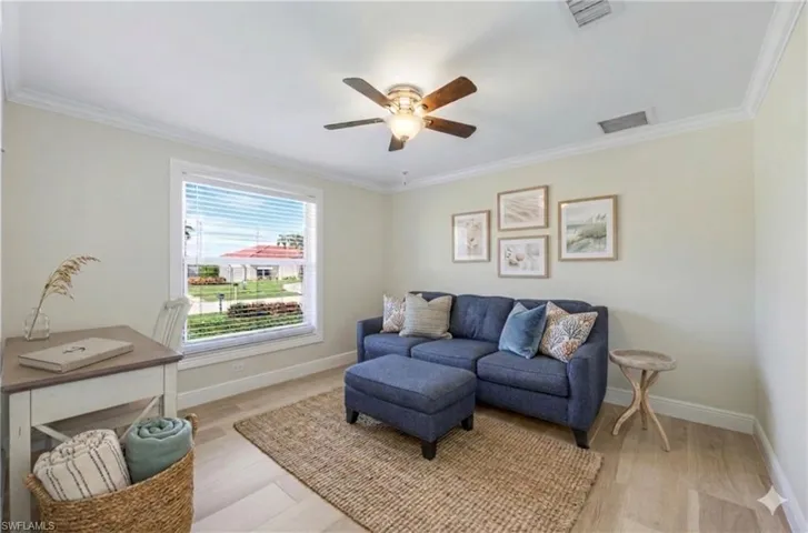 Living area featuring light wood-style flooring, crown molding, and ceiling fan