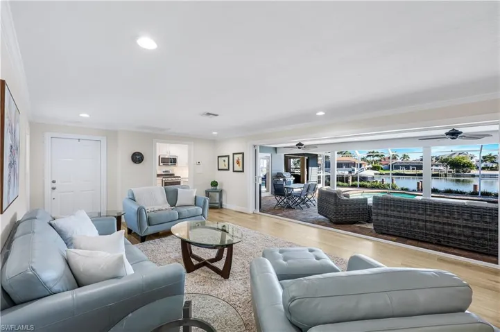Living area featuring a water view, wood finished floors, ornamental molding, recessed lighting, and a sunroom