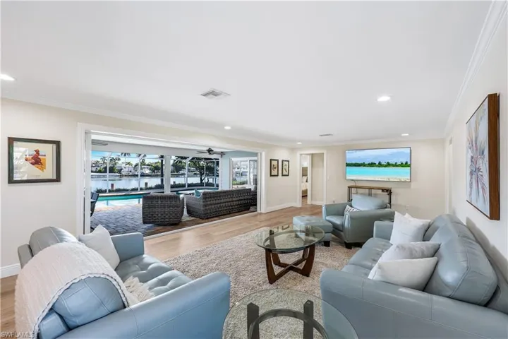 Living area with wood finished floors, ornamental molding, and recessed lighting