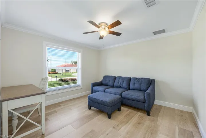 Living area with wood finished floors, ornamental molding, and ceiling fan