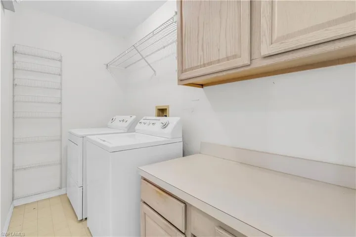 Laundry area with light tile patterned flooring, cabinets, and washer and dryer