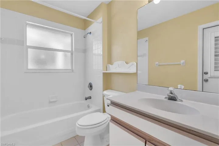 Full bathroom with tiled shower / bath, toilet, tile patterned floors, and vanity
