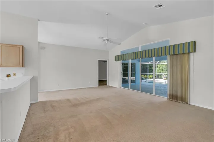 Unfurnished living room featuring ceiling fan, high vaulted ceiling, and light colored carpet
